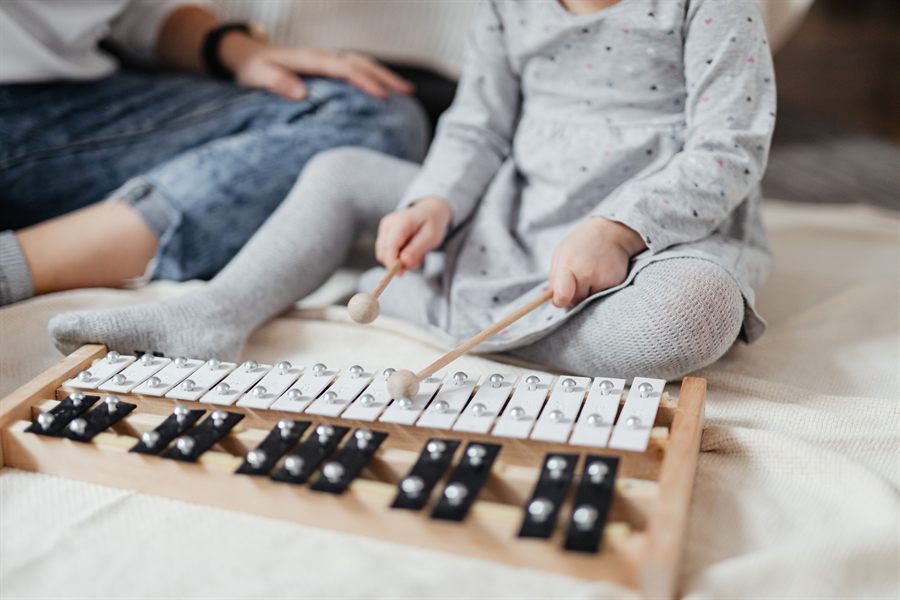 A toddler playing a glockenspiel with a parent